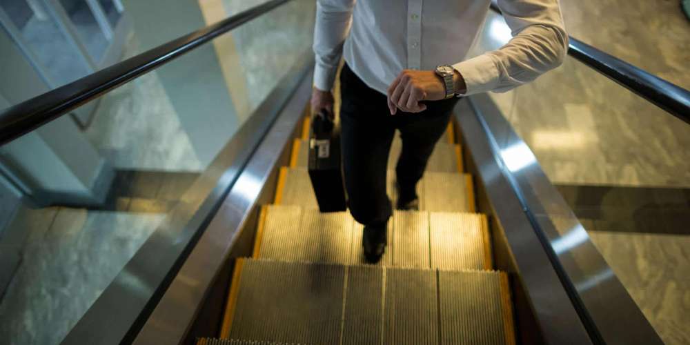 Commuter looking time while walking on escalator in airport